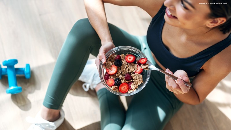 Frau in Sportklamotten mit Müslischüssel