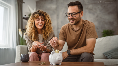 Zwei Personen werfen Geld in ein Sparschwein