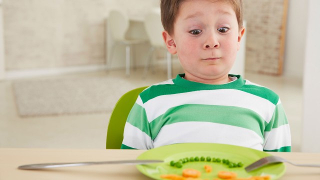 Kind schaut unsicher auf Teller
