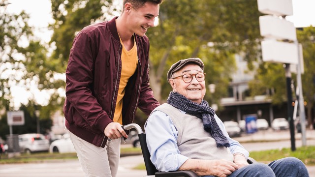 Mann schiebt älteren Mann im Rollstuhl