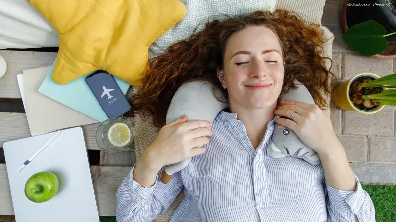 Frau entspannt mit Nackenkissen, Handy im Flugmodus