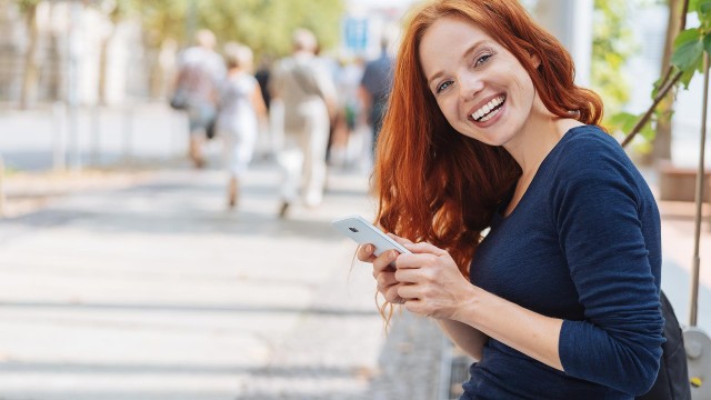 Frau lacht mit Handy.
