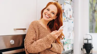Frau lächelt mit einem Smartphone in ihrer Hand