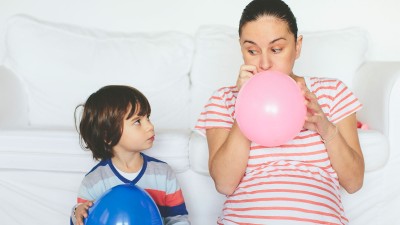 Schwangere Frau pustet Ballon auf