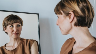 Frau schaut sich im Spiegel an