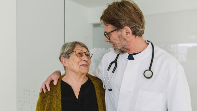 Arzt legt Arm um Patientin