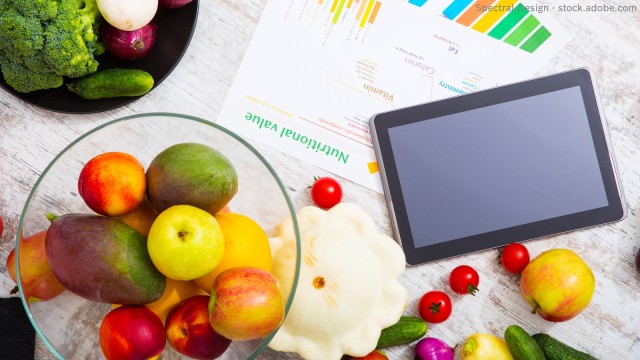 Obst und Gemüse jeweils in einer Schale, daneben ein Tablette und ein ausgedrucktes Blatt mit Daten zu Nährstoffen