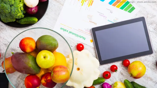 Obst und Gemüse jeweils in einer Schale, daneben ein Tablette und ein ausgedrucktes Blatt mit Daten zu Nährstoffen