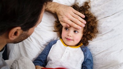 Vater hält Hand auf die Stirn vom Kind.