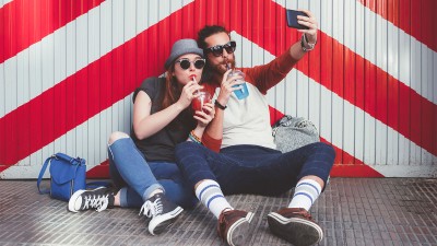 Eine Frau und ein Mann trinken aus Bechern und machen ein Selfie