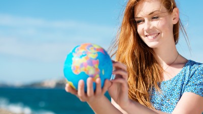 Junge Frau mit Globus am Meer