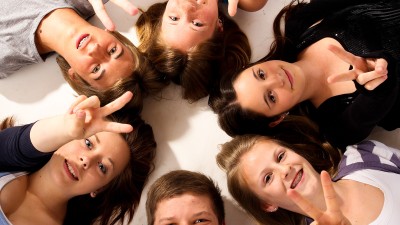 Junge Menschen liegen im Kreis auf dem Boden und lächeln in die Kamera