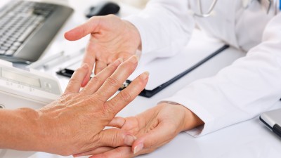 Eine Ärztin hält die Hand einer Patientin zur Untersuchung.