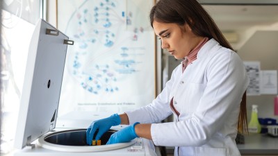 In einem Labor untersucht eine junge Frau Blut.