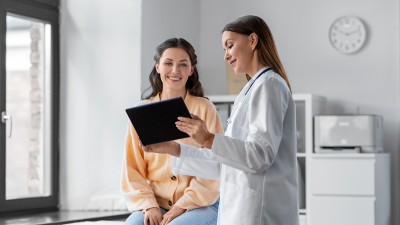 Ärztin zeigt einer Patientin in einer Praxis Gesundheitsdaten auf einem Tablet – symbolische Darstellung der digitalen Patientenakte.