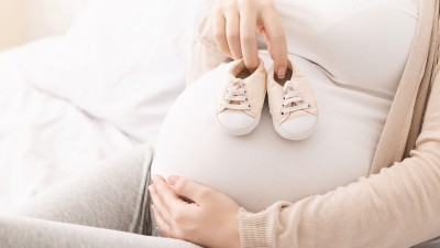 Schwangere Frau mit Babyschuhen auf Bauch