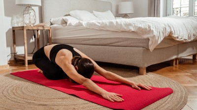 Eine Frau macht Yoga in ihrem Schlafzimmer.
