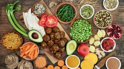 Blick von oben auf einen Holztisch, auf dem gesunde Lebensmittel stehen.