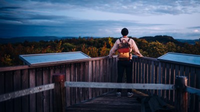 Ein Mann steht an einem Geländer und blickt in die Landschaft.