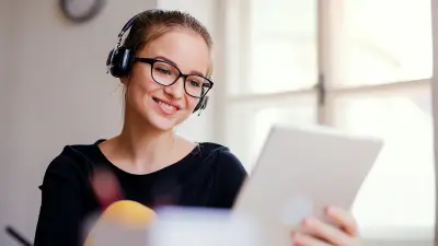 Eine junge Frau sitzt zum Lernen am Tablet.