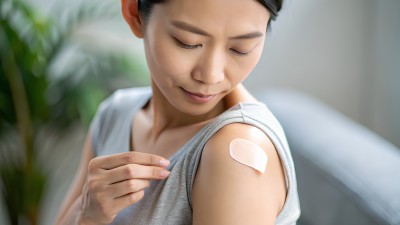 Eine Frau klebt sich ein Nikotinpflaster auf den Oberarm.