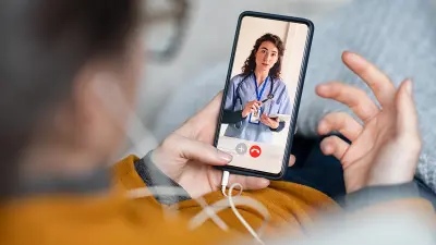 Beratung über das Handy: Eine Person nimmt eine digitale Sprechstunde mit einer Ärztin in Anspruch.
