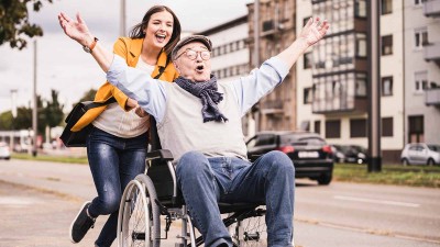 Frau schiebt Mann im Rollstuhl