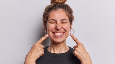 Frau zeigt auf ihr Lächeln