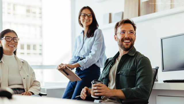 Drei Personen lachen beim Arbeiten